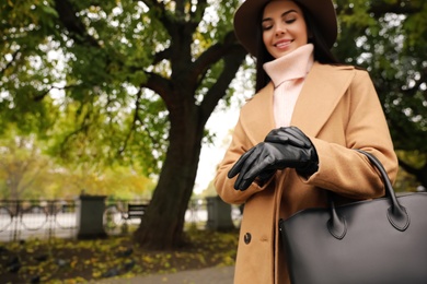 Photo of Young woman in black leather gloves, focus on hands. Stylish clothes