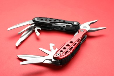 Photo of Compact portable multitool on red background, closeup