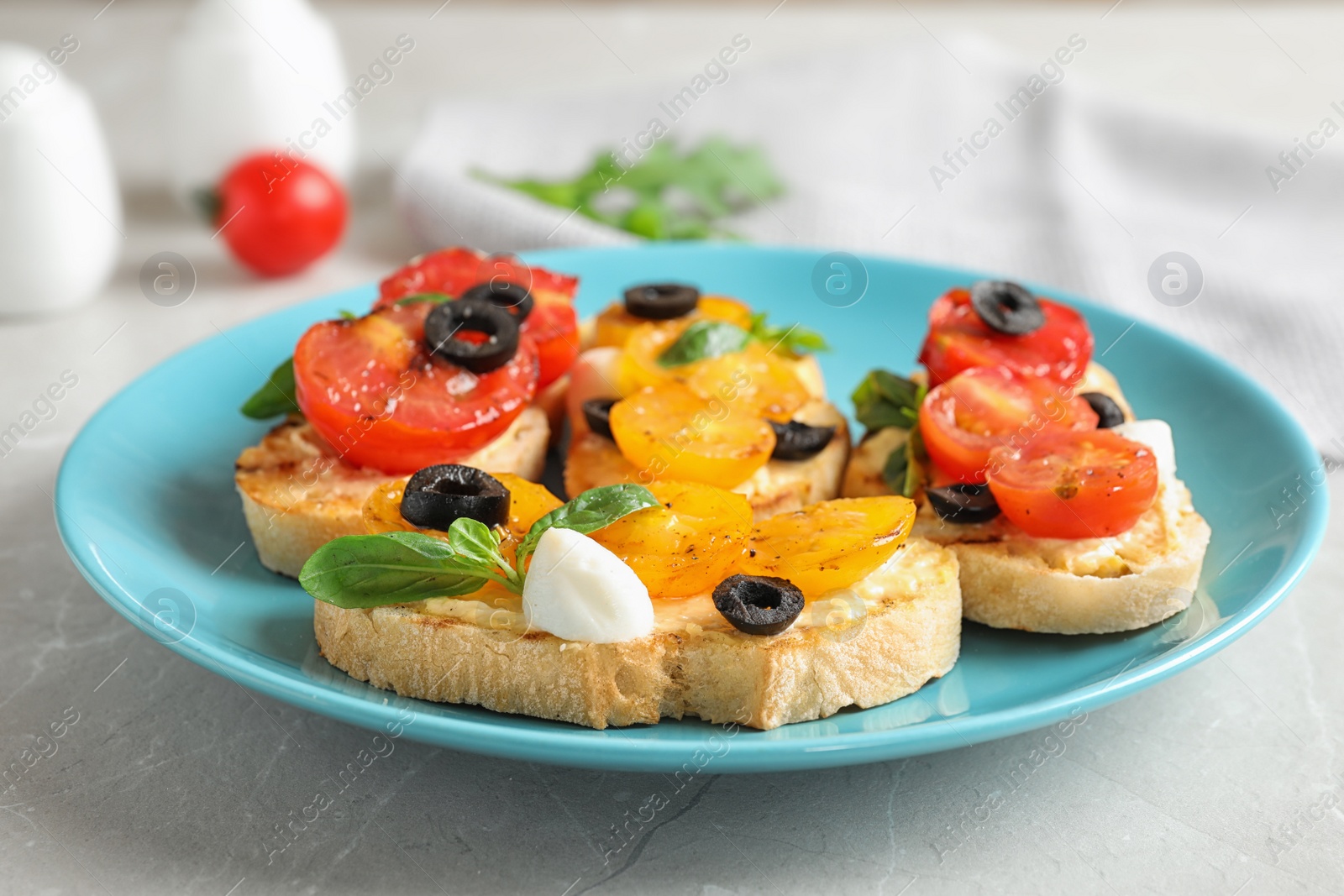 Photo of Plate of delicious tomato bruschettas on light grey marble table