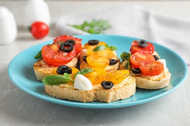 Plate of delicious tomato bruschettas on light grey marble table