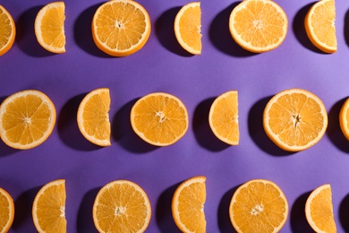 Photo of Slices of delicious oranges on purple background, flat lay