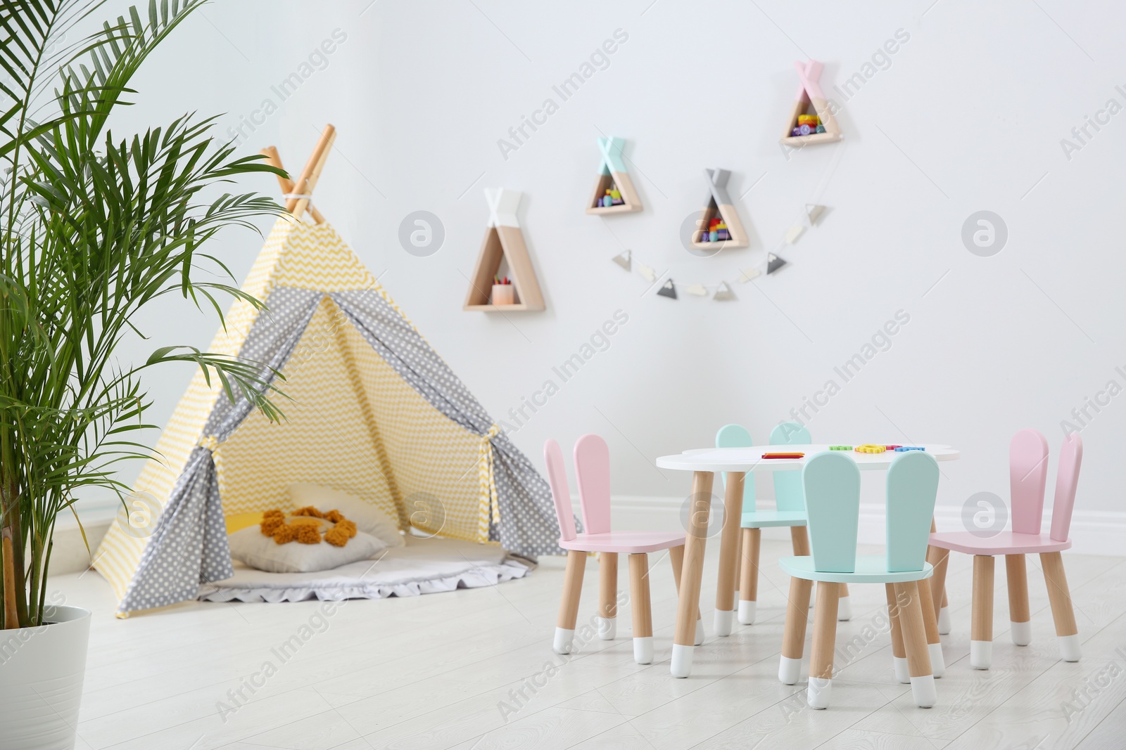 Photo of Cute children's room interior with teepee tent and little table