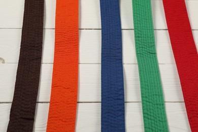 Colorful karate belts on wooden background, flat lay