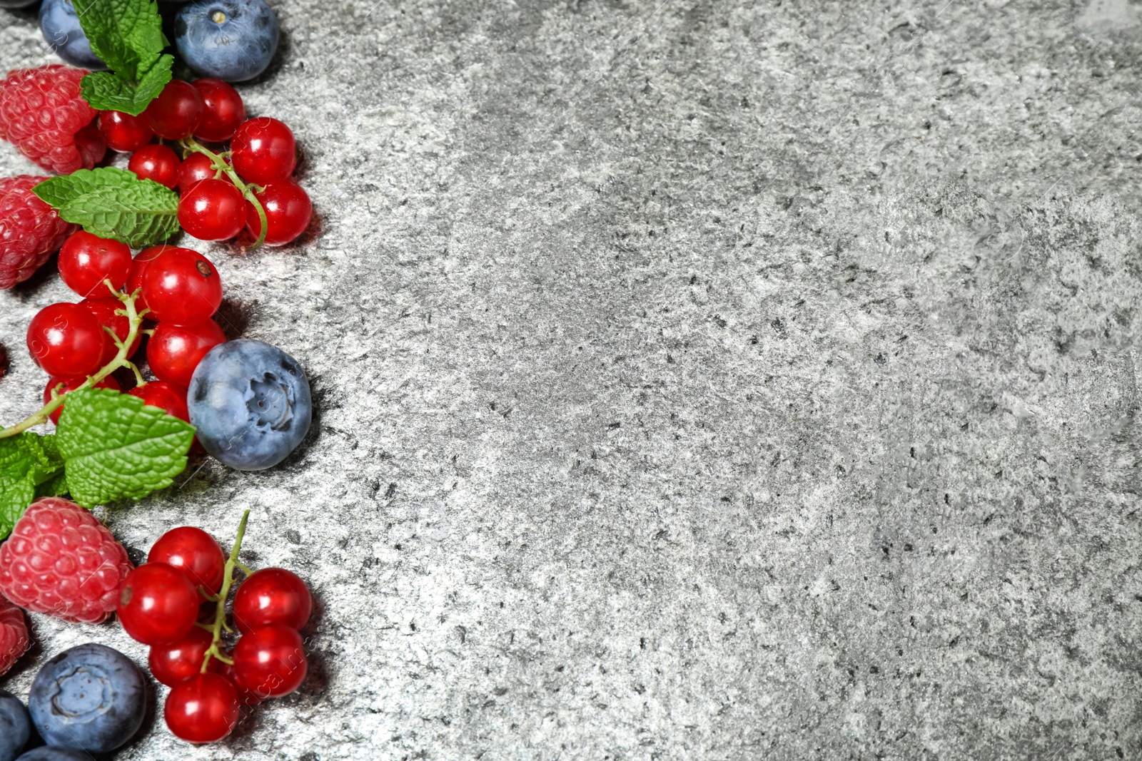 Photo of Different fresh berries on grey background, flat lay. Space for text