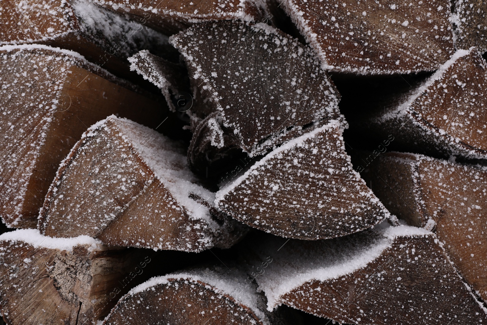 Photo of Stacked firewood with snow and hoarfrost as background, closeup