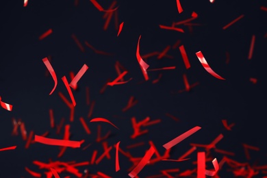 Photo of Shiny red confetti falling down on dark blue background