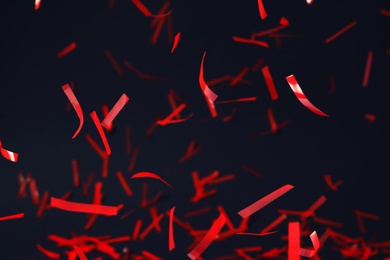 Shiny red confetti falling down on dark blue background