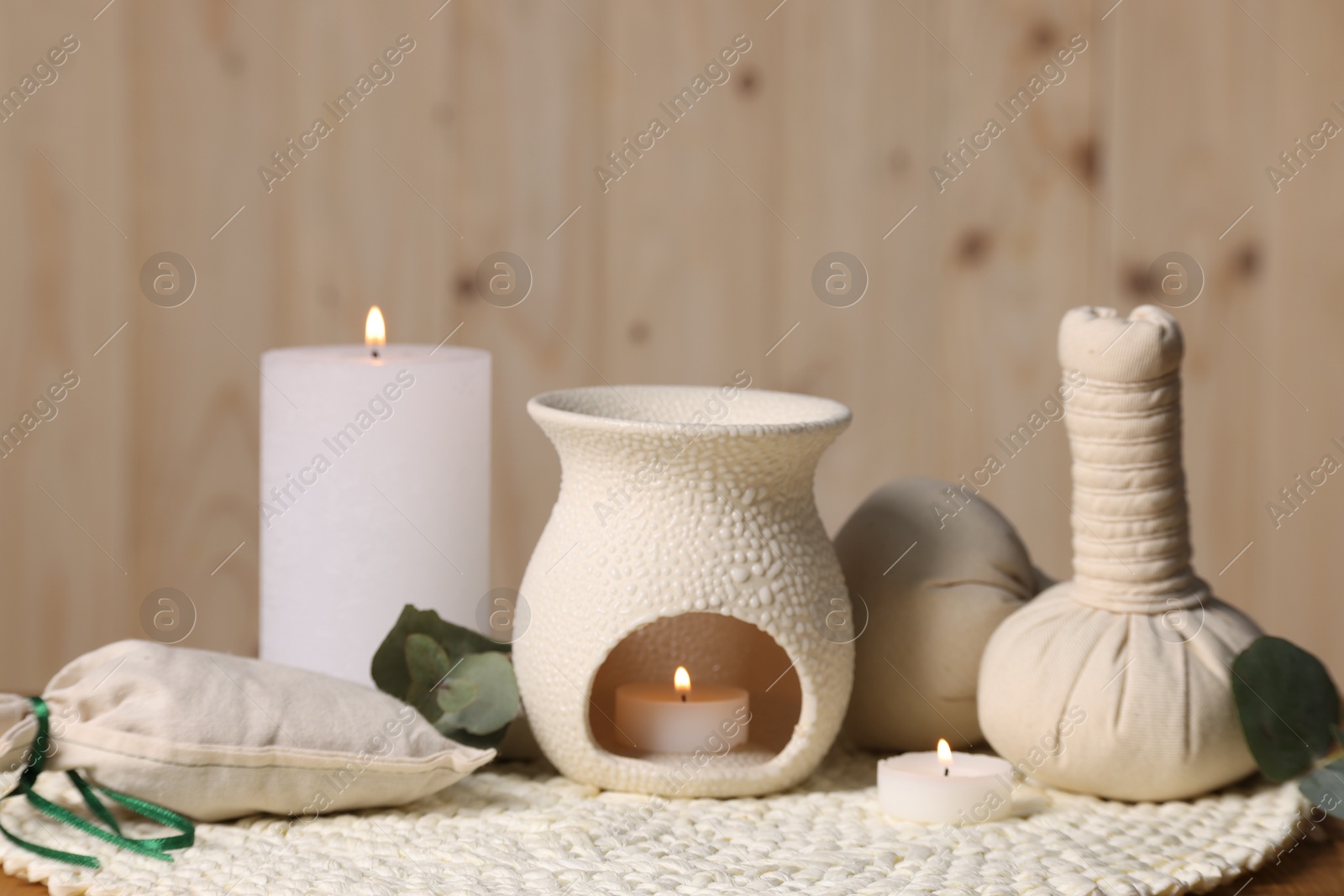 Photo of Different aromatherapy products, burning candles and eucalyptus leaves on table