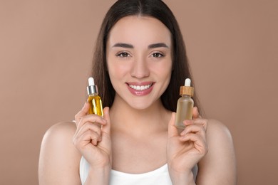 Woman with bottles of essential oil on brown background