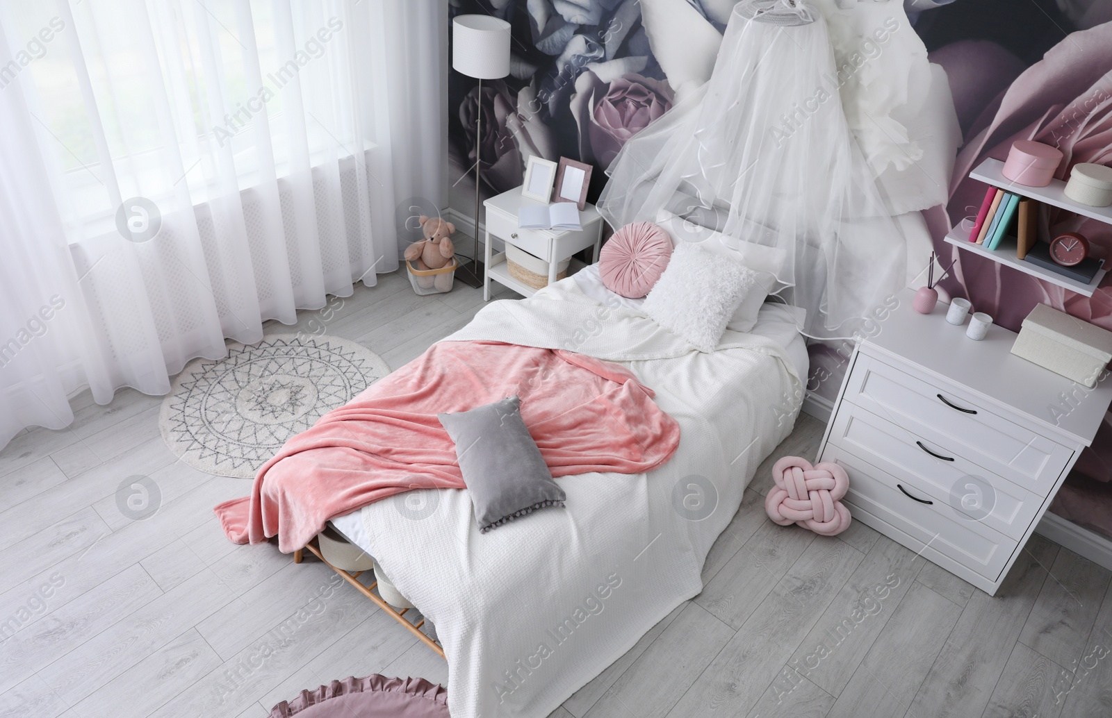 Photo of Teenage girl's room interior with comfortable bed and floral wallpaper. Idea for stylish design