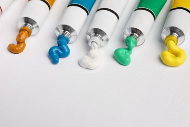 Photo of Tubes with oil paints on white canvas, closeup. Space for text