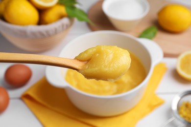 Photo of Taking delicious lemon curd from bowl at table, closeup