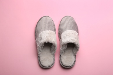 Photo of Pair of soft slippers on light pink background, flat lay