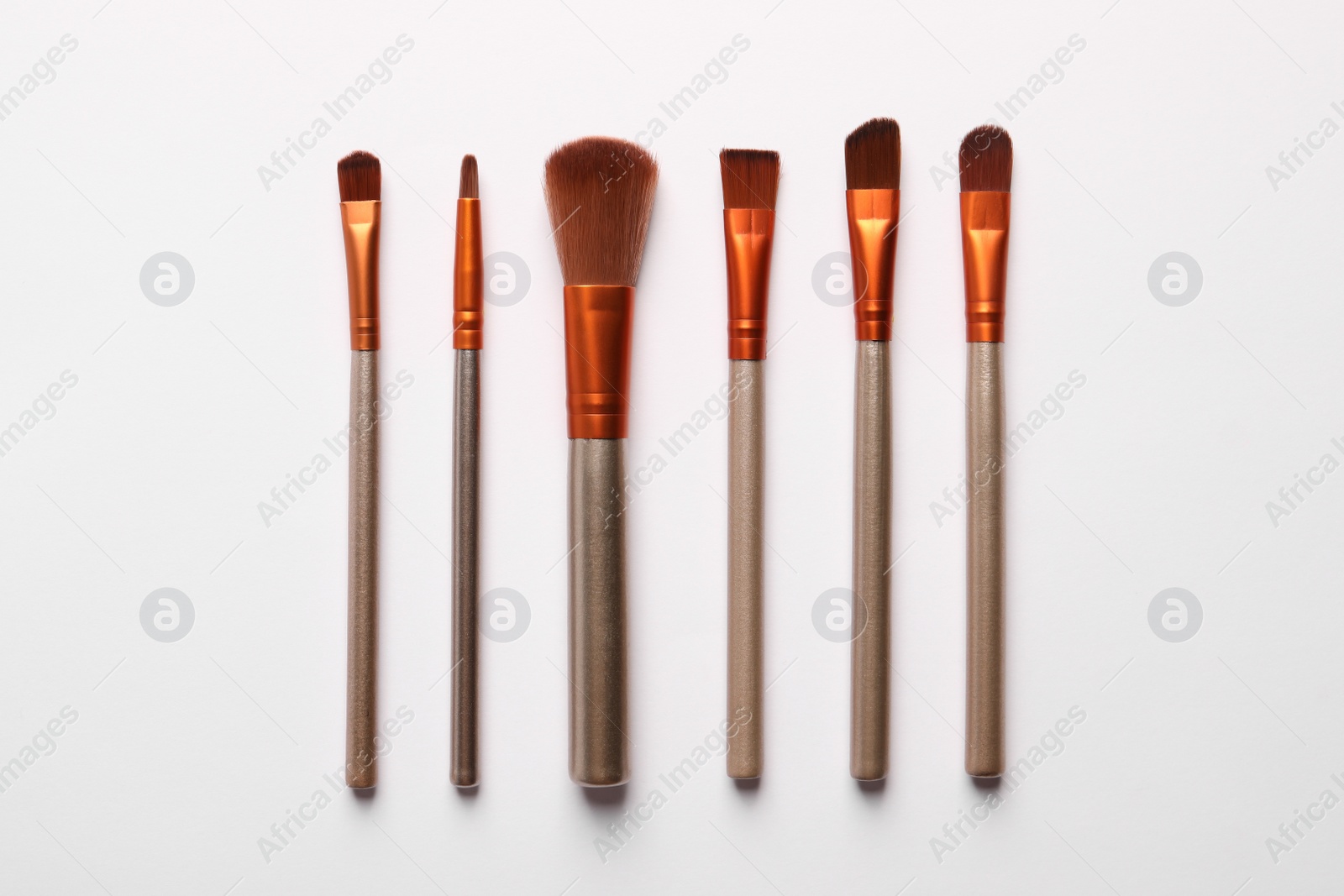 Photo of Different makeup brushes on white background, flat lay