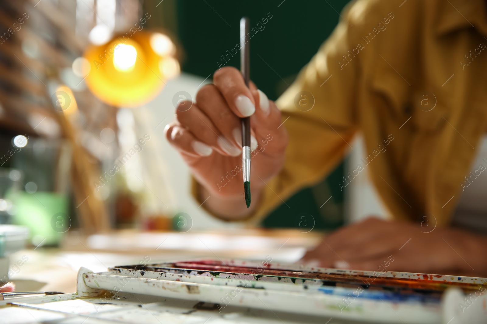 Photo of Young woman drawing with watercolors at table, closeup