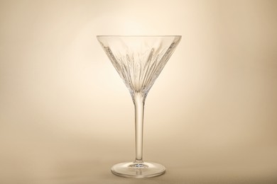 Photo of Elegant empty martini glass on beige background