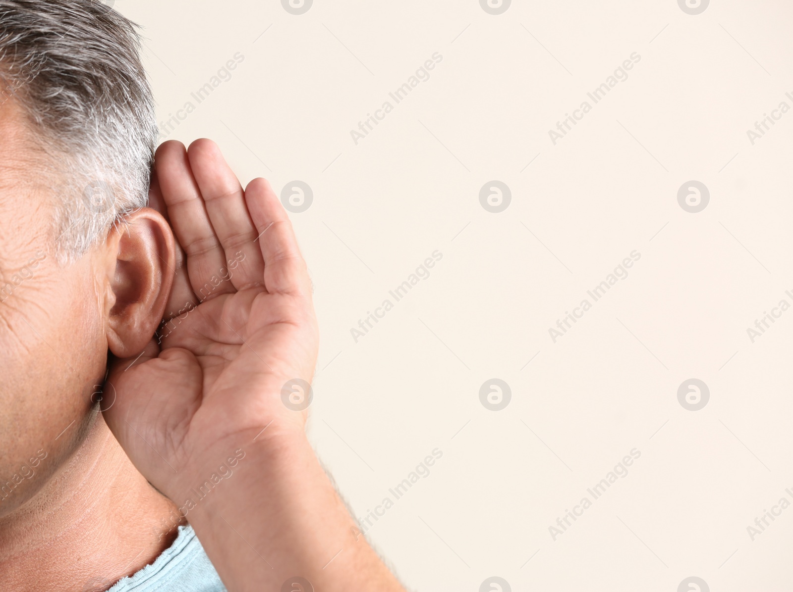 Photo of Mature man with hearing problem on light background, closeup. Space for text