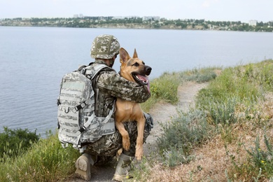 Photo of Man in military uniform with German shepherd dog outdoors