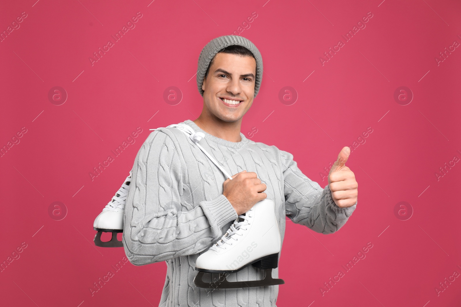 Photo of Happy man with ice skates on pink background