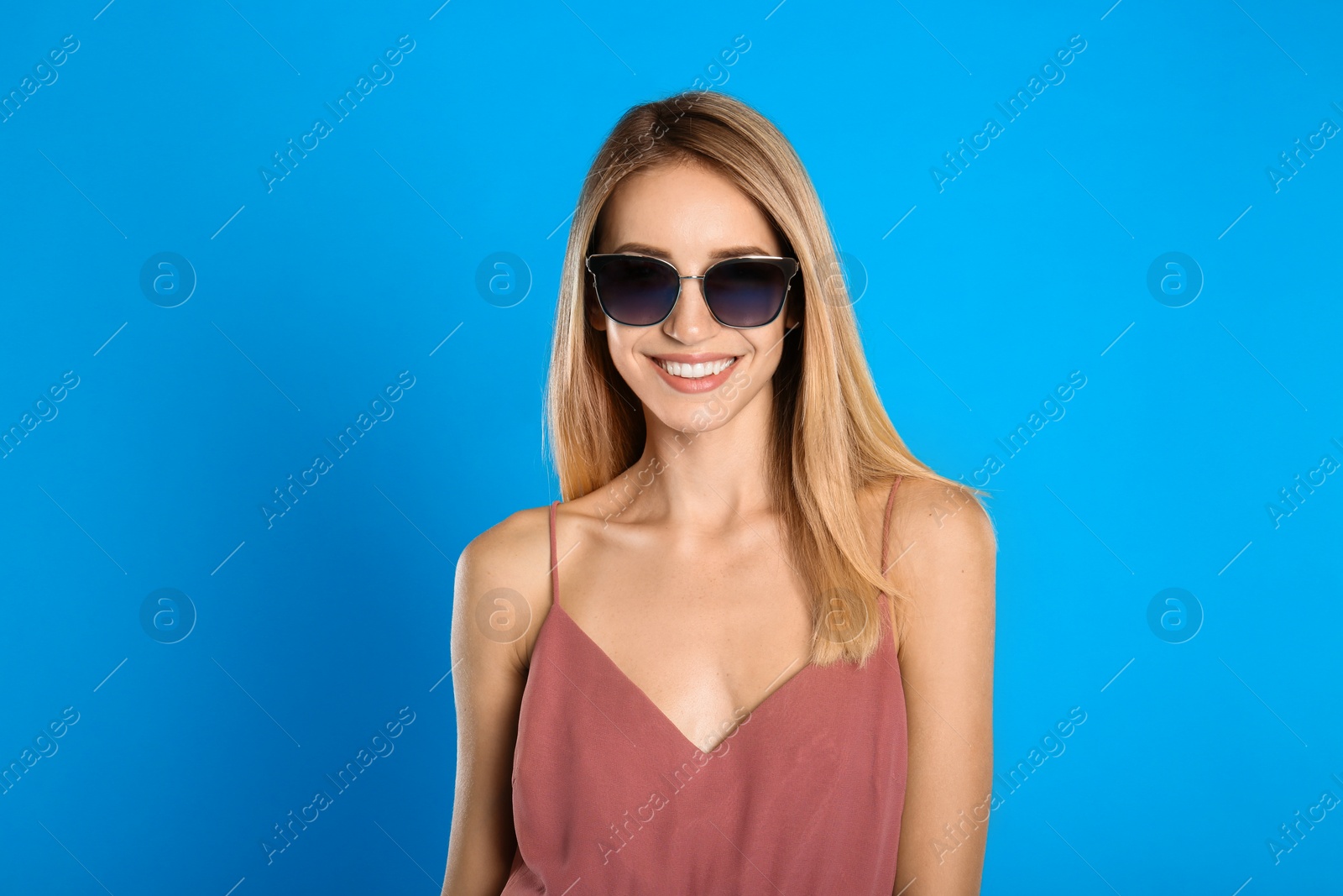 Photo of Beautiful woman in stylish sunglasses on light blue background