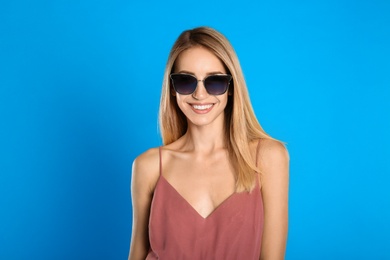 Beautiful woman in stylish sunglasses on light blue background