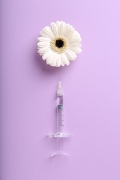 Photo of Cosmetology. Medical syringe and gerbera flower on violet background, flat lay