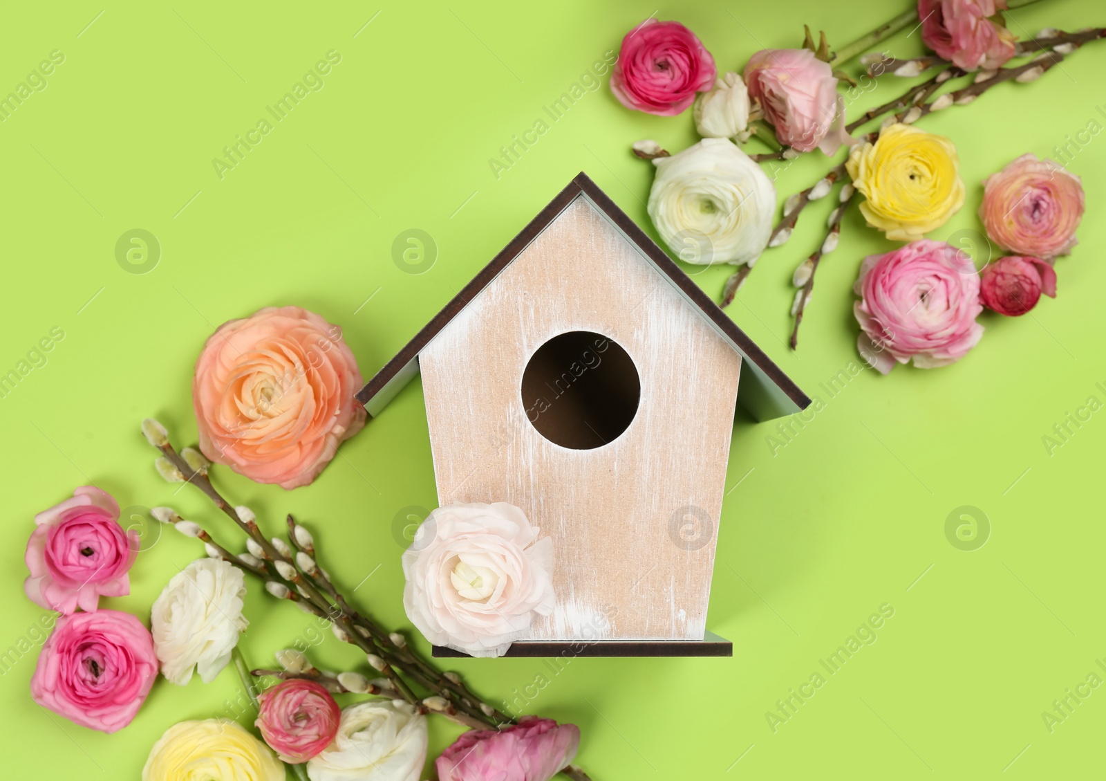 Photo of Stylish bird house and fresh flowers on green background, flat lay