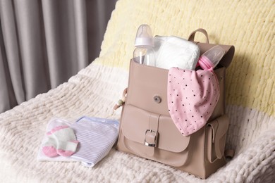 Photo of Mother's bag with baby's stuff on armchair indoors