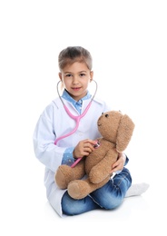 Photo of Cute child playing doctor with stuffed toy on white background