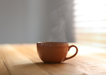 Photo of Cup of delicious coffee on wooden table, space for text. Good morning