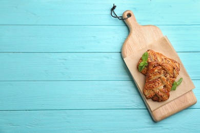 Photo of Fresh delicious puff pastry on light blue wooden table, top view. Space for text