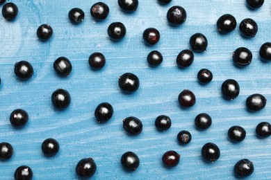 Photo of Ripe elderberries on light blue wooden table, flat lay