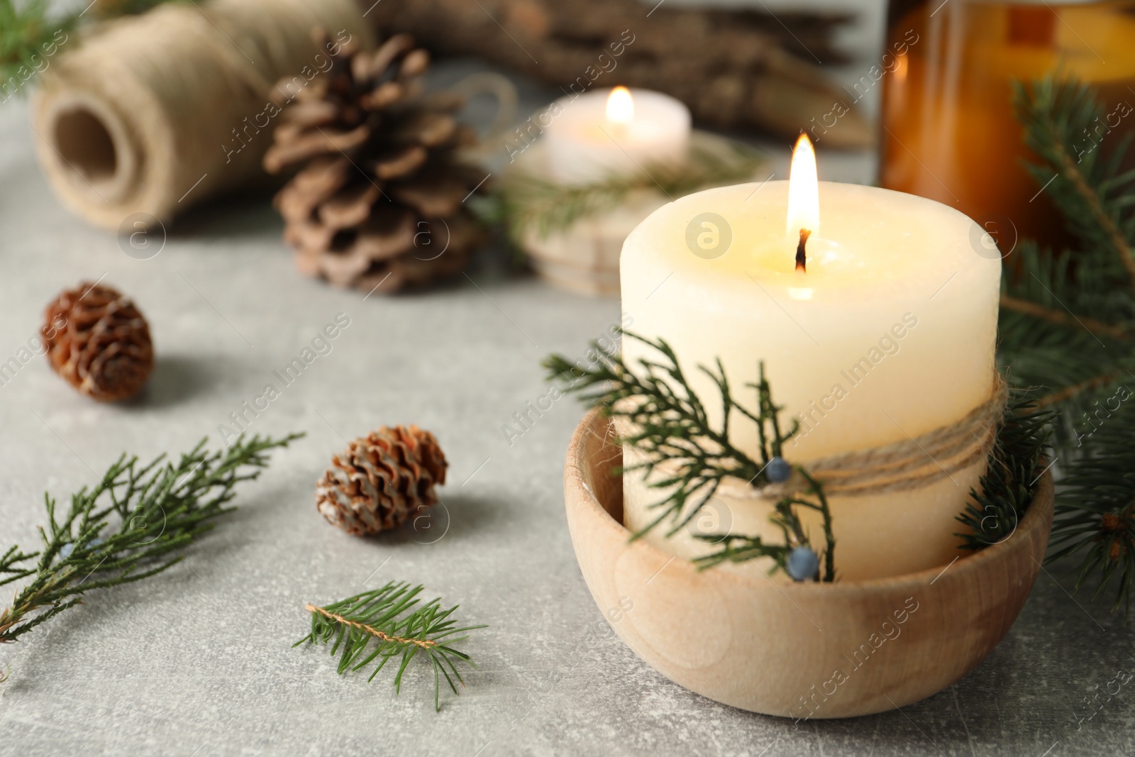 Photo of Burning candle with pinecone scent on light grey table, space for text