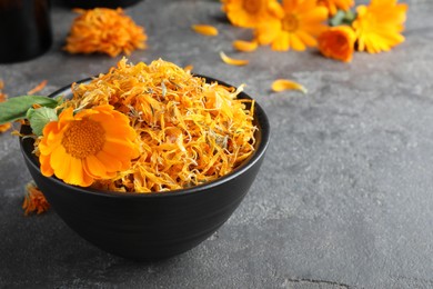 Bowl of dry and fresh calendula flowers on grey table. Space for text