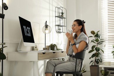 Young woman with cup of tea working at table in light room. Home office