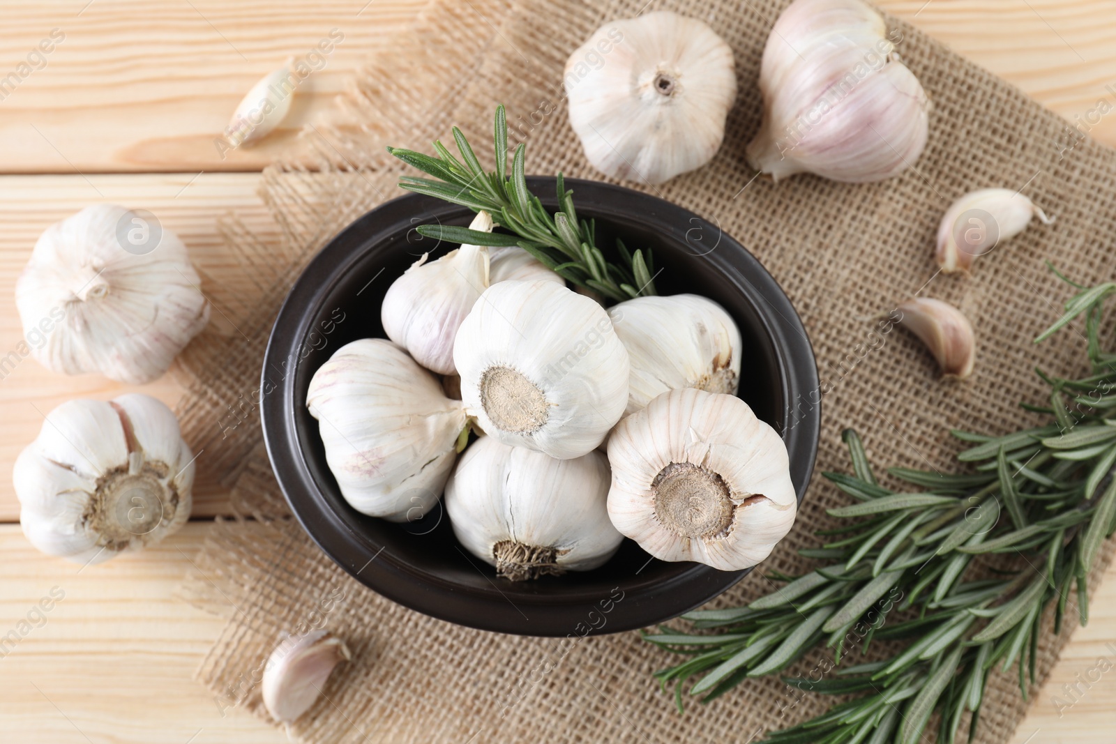 Photo of Fresh raw garlic and rosemary on wooden table, flat lay