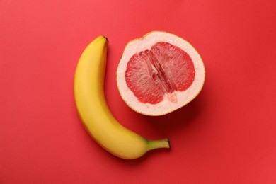 Photo of Banana and half of grapefruit on red background, flat lay. Sex concept