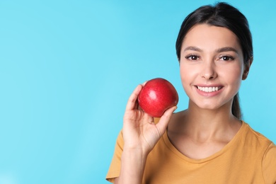 Photo of Young woman with healthy teeth and apple on color background. Space for text