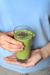 Photo of Woman holding glass of fresh green smoothie with chia seeds, closeup
