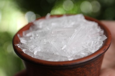 Photo of Menthol crystals in bowl against blurred background, closeup
