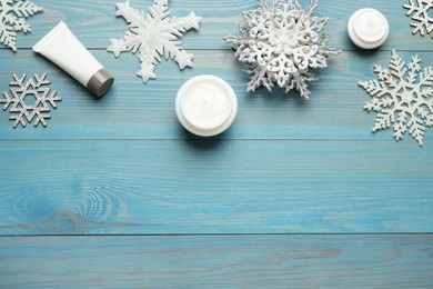 Flat lay composition with cosmetic products and snowflakes on turquoise wooden table, space for text. Winter skin care