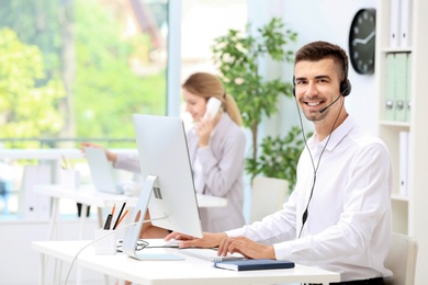 Photo of Male receptionist with headset at desk in office