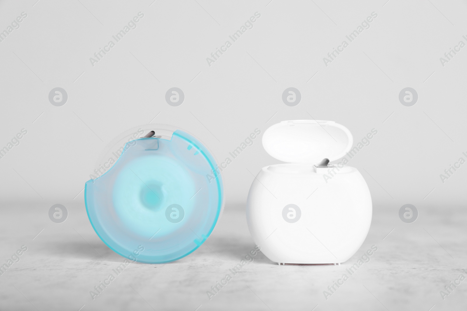 Photo of Containers with dental floss on light grey textured table
