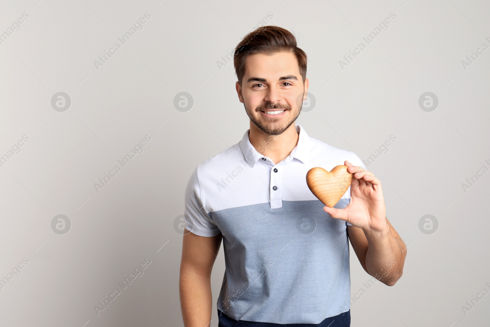 Photo of Portrait of young man with decorative heart on light background. Space for text