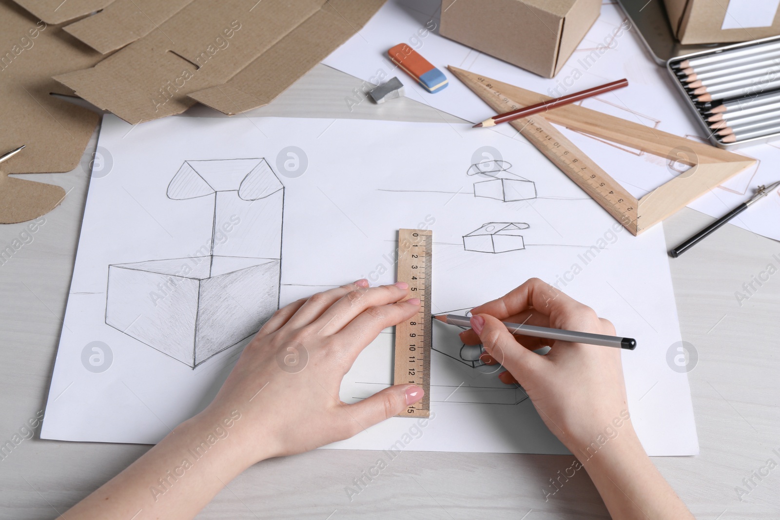 Photo of Woman creating packaging design at light wooden table, closeup