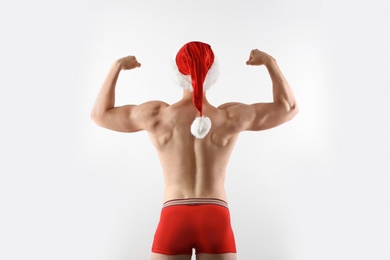 Photo of Young muscular man in Santa hat on white background