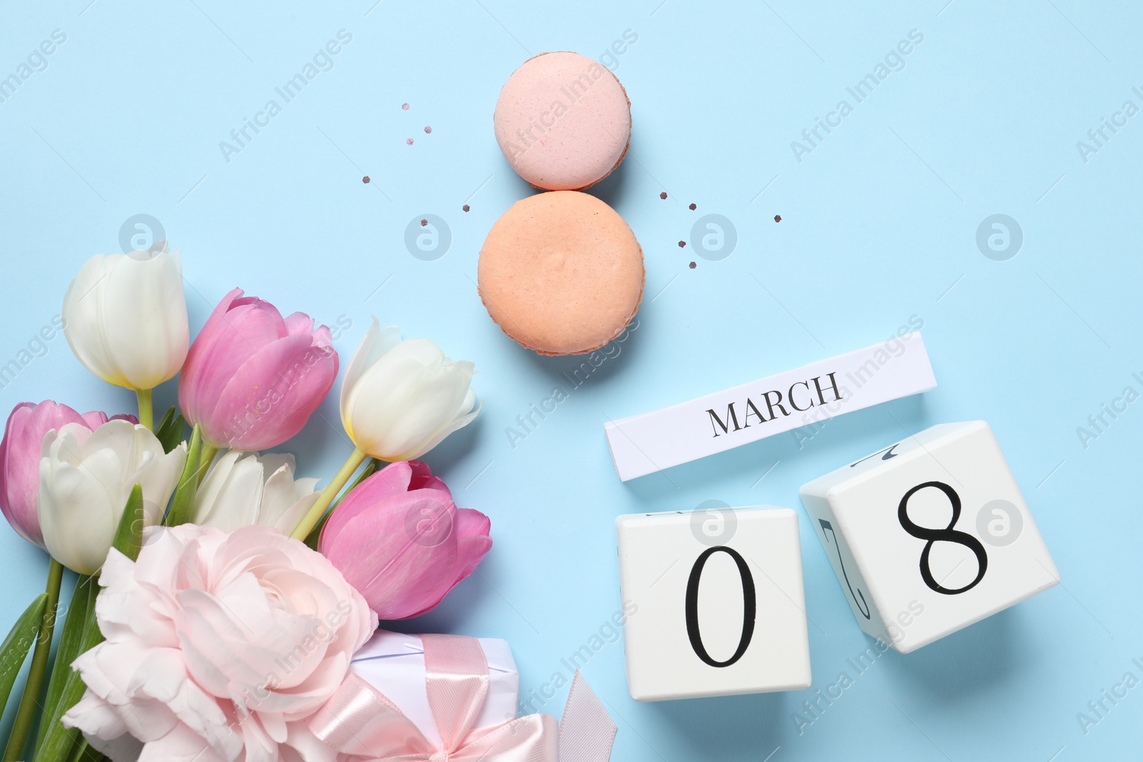 Photo of International Women's day - 8th of March. Macaron cookies, wooden block calendar and beautiful flowers on light blue background, flat lay