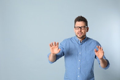 Photo of Man with vision problems wearing glasses on grey background, space for text