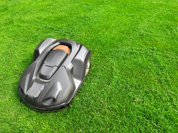 Photo of Modern robot lawn mower on green grass in garden