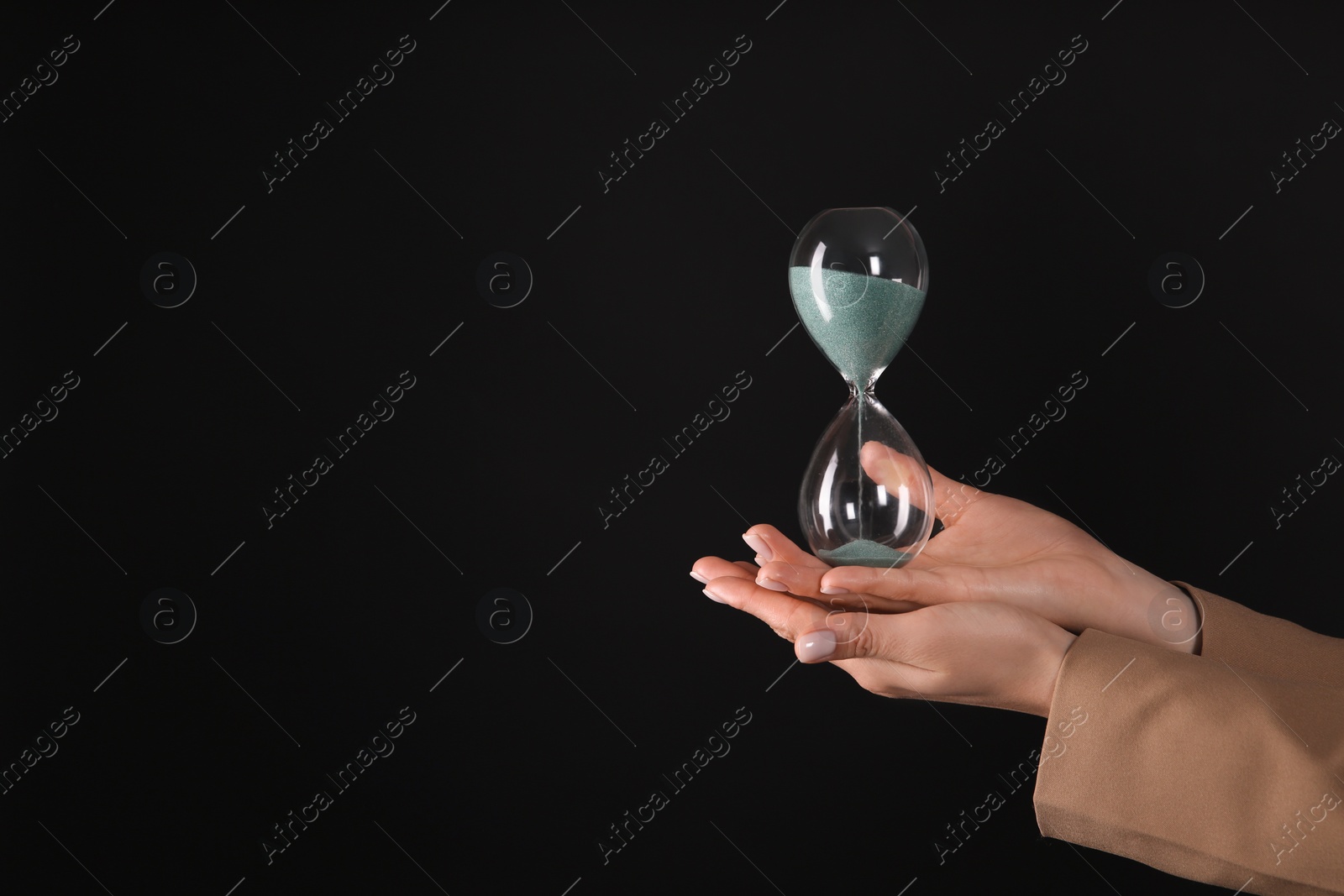 Photo of Businesswoman holding hourglass on black background, closeup with space for text. Time management